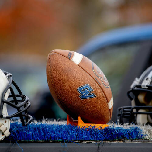 Photo of GVSU football helmets on table with a football in center.
